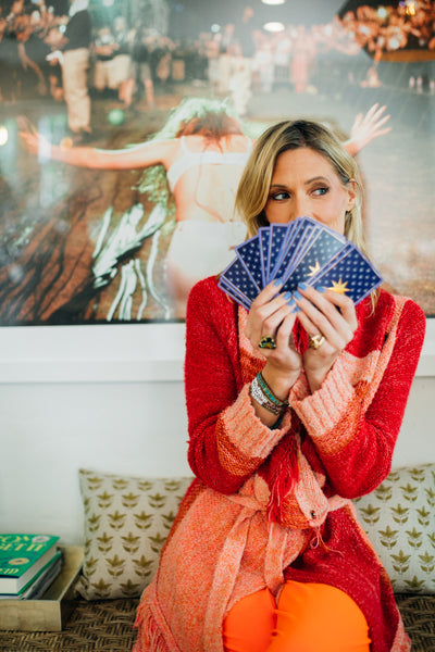 Woman in a red sweater holding tarot cards in front of a blurred background