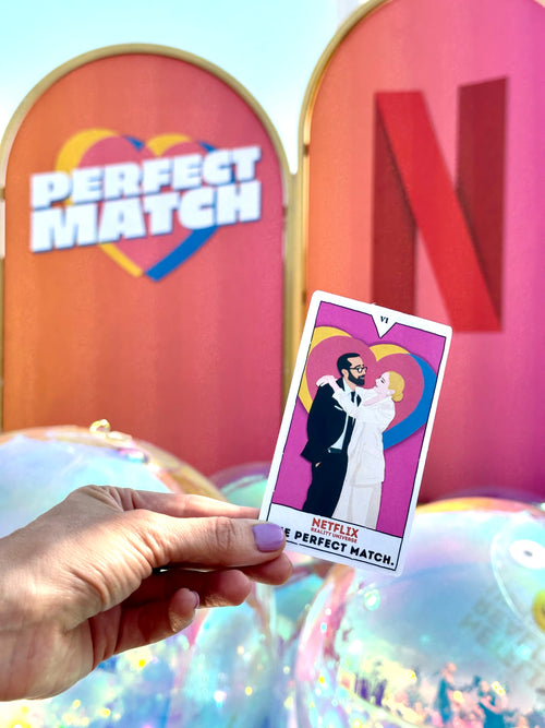 Hand holding a card with 'Perfect Match' design in front of a 'Netflix' backdrop