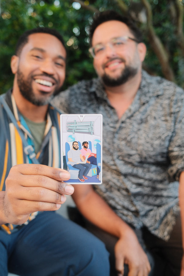 Two people holding a card with a printed image of a couple outdoors.